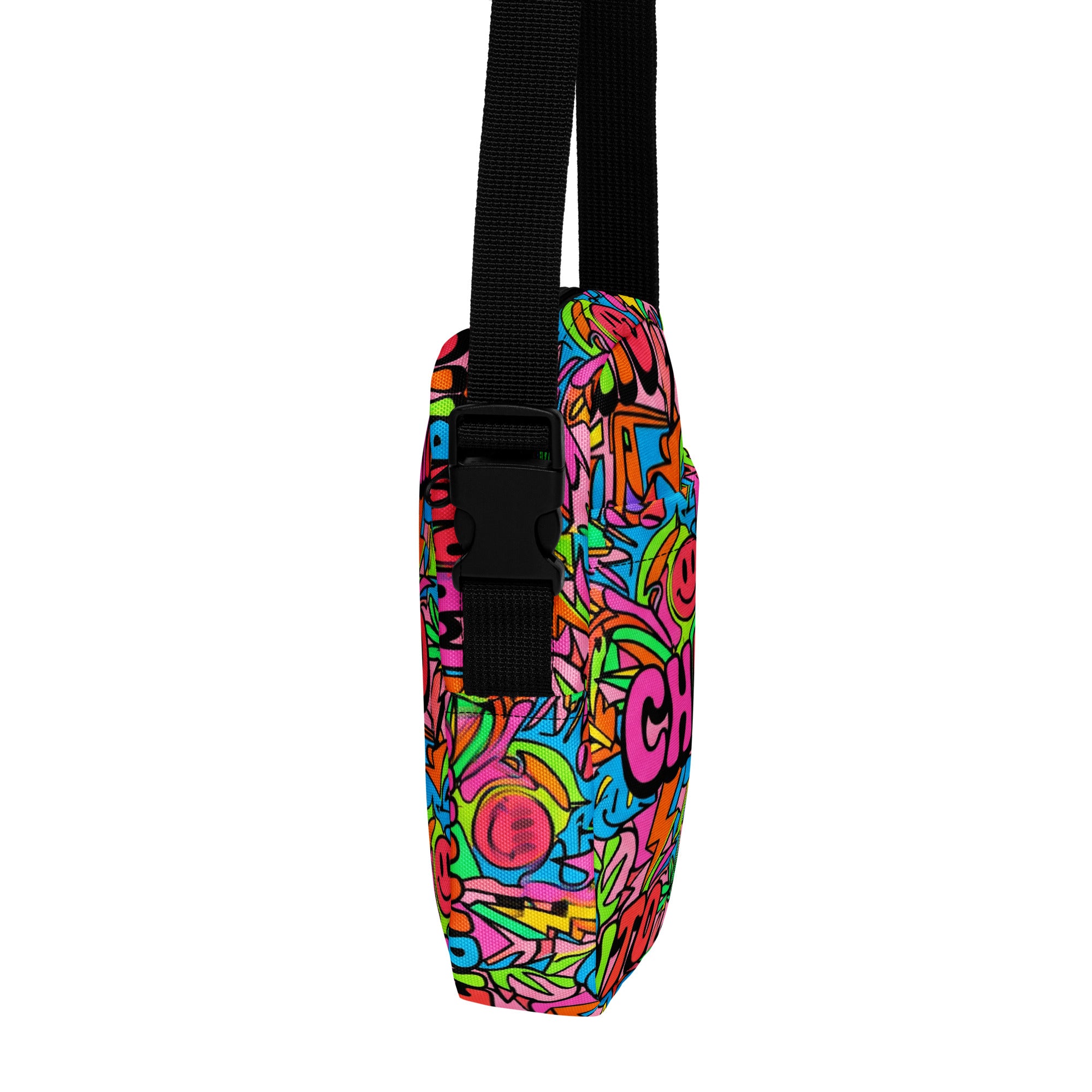 A vertical shoulder bag with a vibrant, multicolored graffiti-style pattern featuring pink, blue, green, and yellow, complete with a black adjustable webbing strap and plastic buckle.