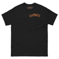 A black short-sleeve crewneck t-shirt with 'CHAMBITO' printed in orange arched text across the chest, and a matching orange and black brand label inside the collar.
